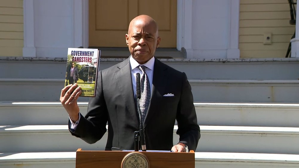 Mayor Adams holds a book.