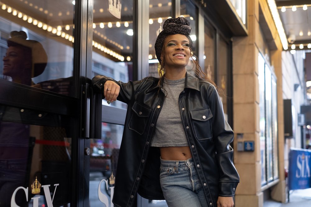 An actress poses in front of a Broadway theater.