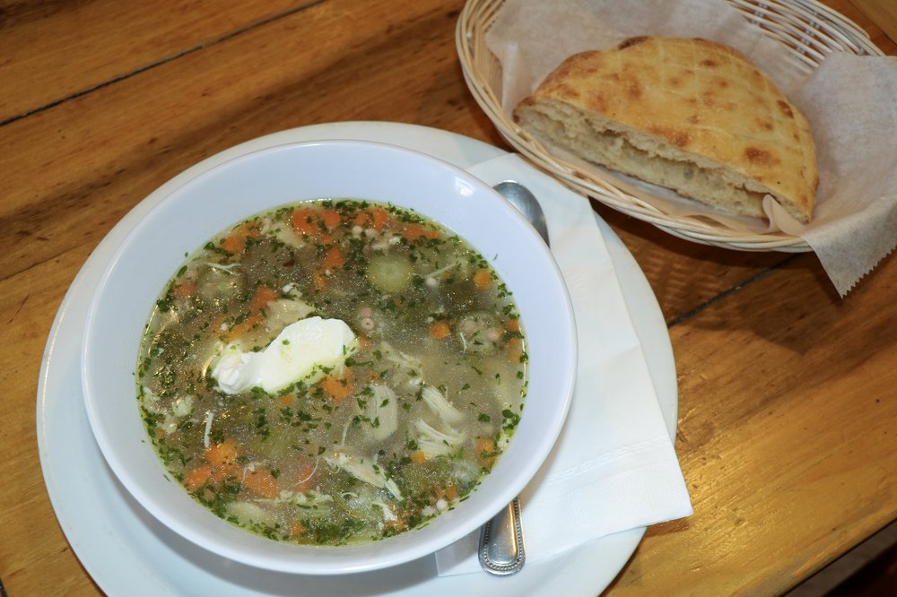 A soup in a bowl with carrots and okra with a side of bread.