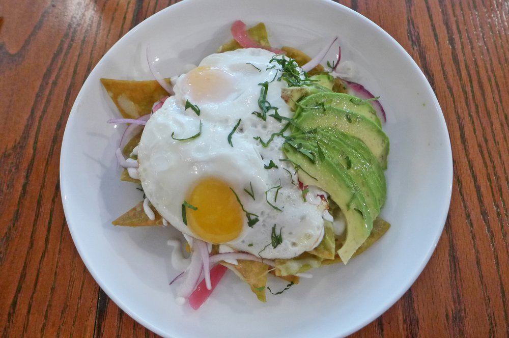 A bowl with sliced avocadoes and poached eggs.