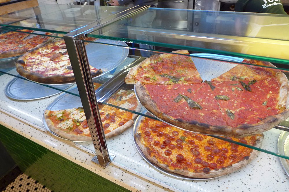 An array of pizzas on a counter.