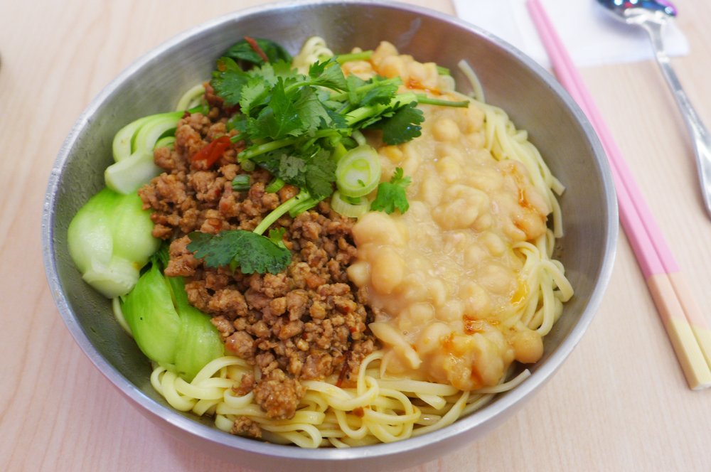 A bowl of noodles with chopsticks on the side.