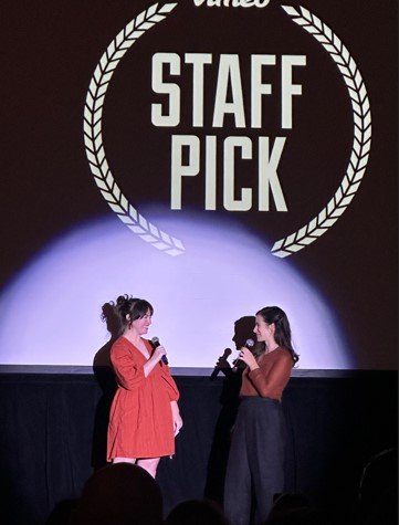 Two women stand on a stage.