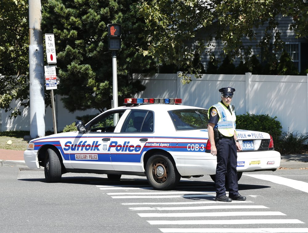 A police officer stands in front of a police car.