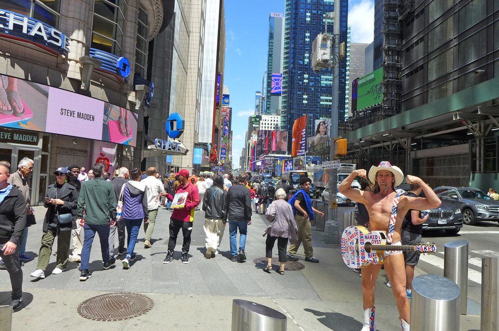 Pedestrians and the Naked Cowboy in Times Square.