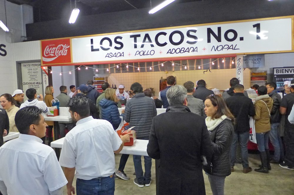 People in line for tacos at a taco stand.