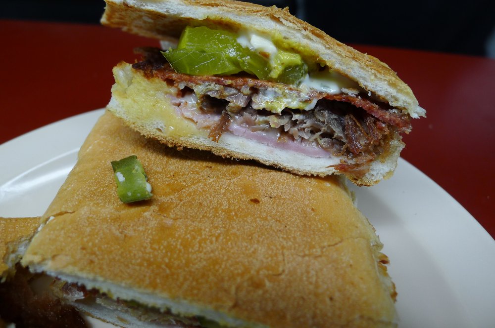 A sandwich layered with ham, cheese and pickles.