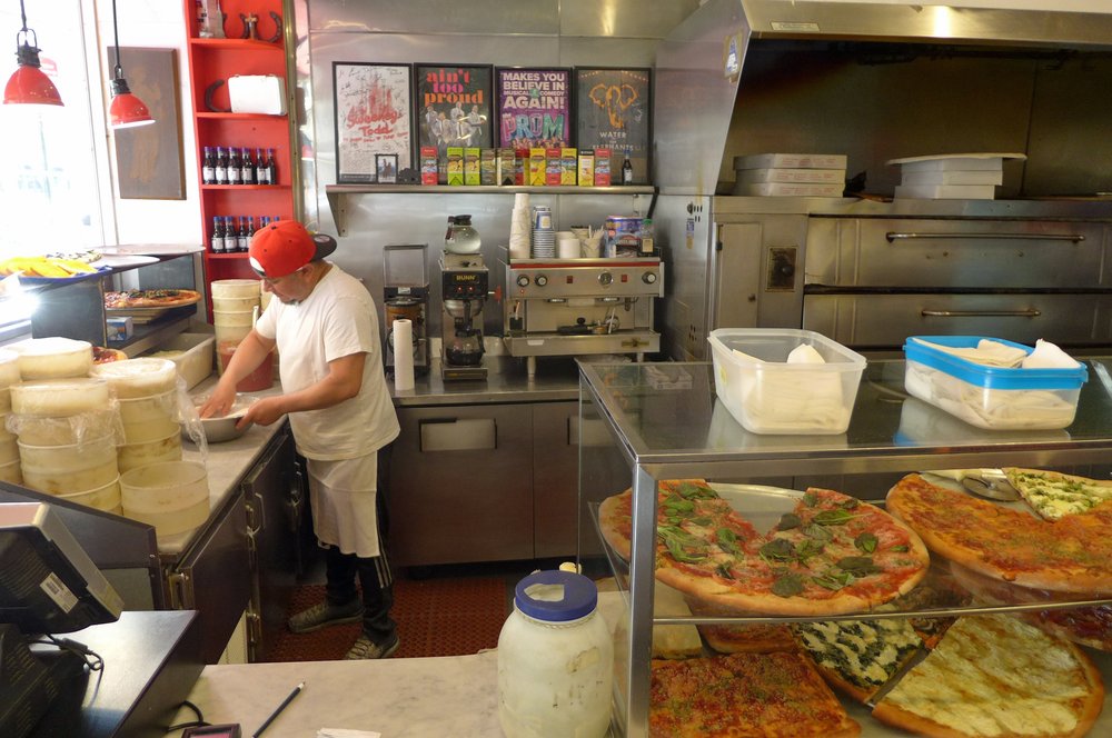 A man makes pizzas in a pizzeria.