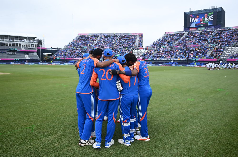 A group of athletes huddles on a field.