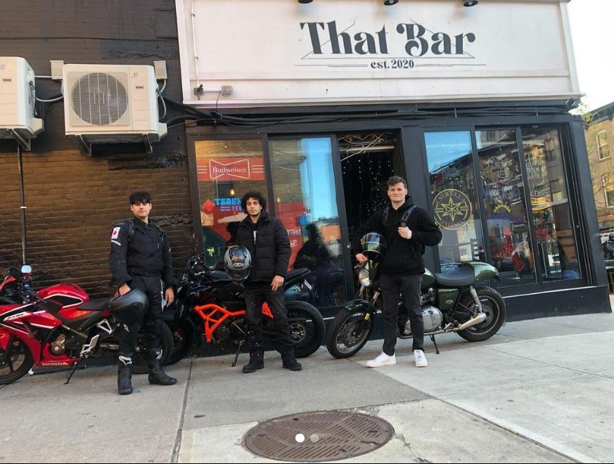A picture of motorcycles in front of a bar with a sign that says "That Bar."
