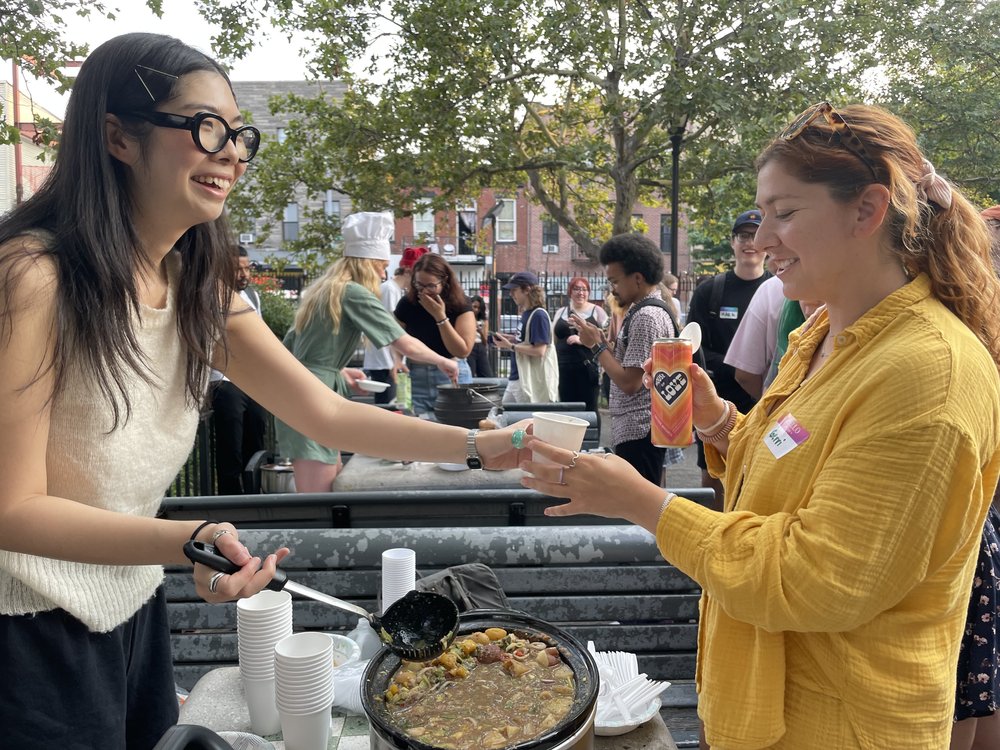 A woman hands the stew to a guest