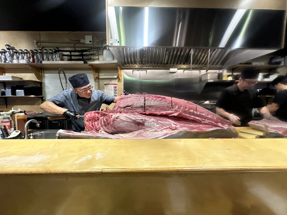 A man carves an enormous tuna fish.