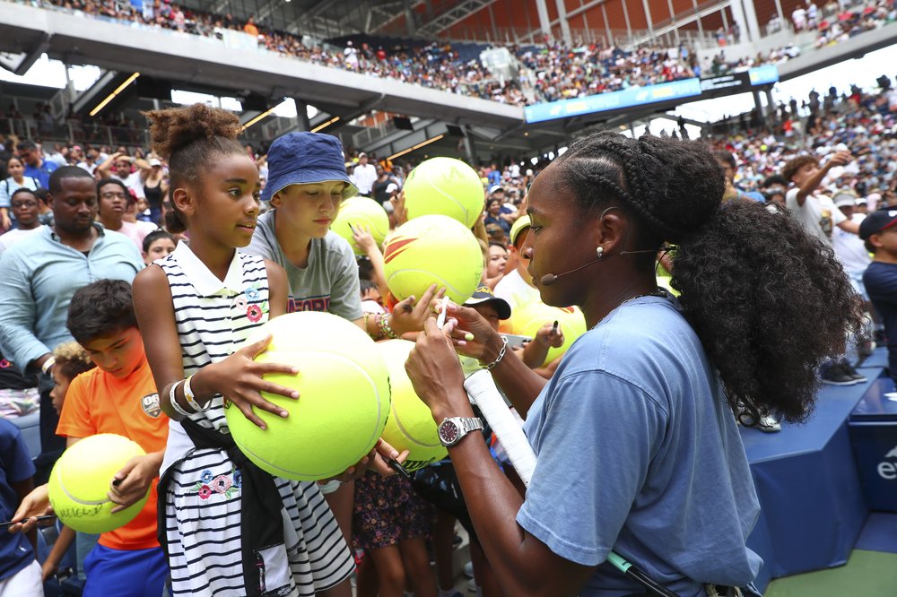 A tennis player signs autographs for children.