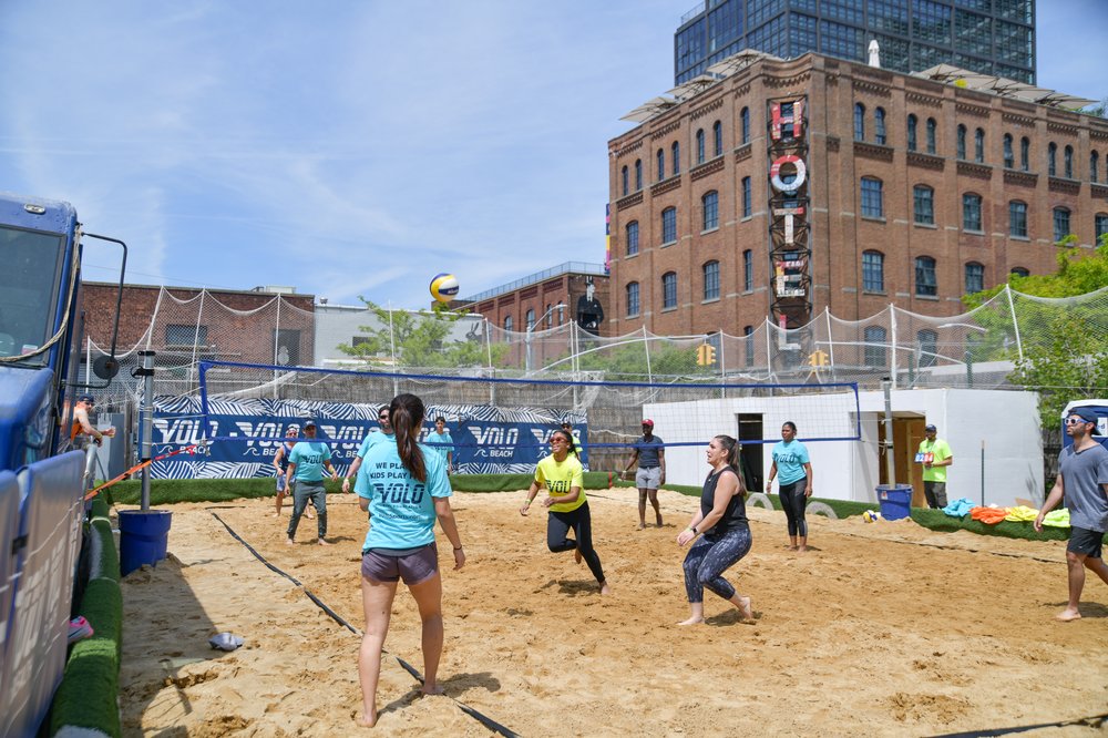 A beach volleyball court surrounded by Brooklyn buildings.