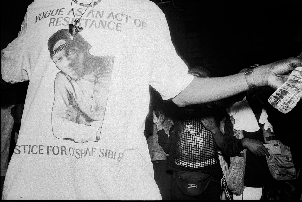A person wears a t-shirt that reads: "Vogue as an act of resistance. Justice for O'Shae Sibley."