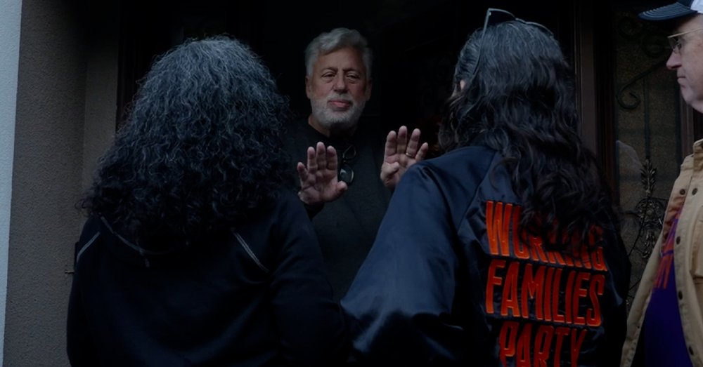 A group of people speak with a man at a home.
