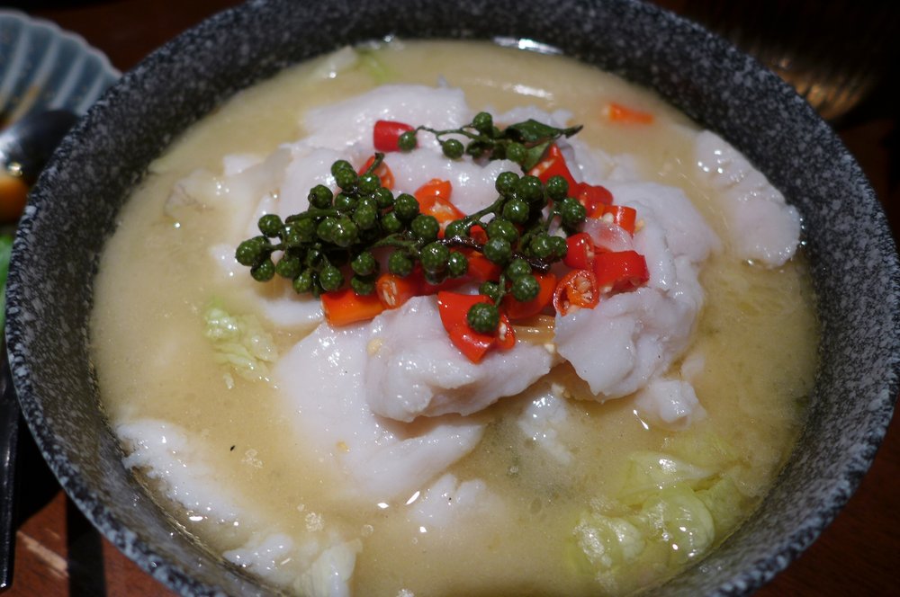 A green fish stew photographed from above with a dollop of a white creamy substance.