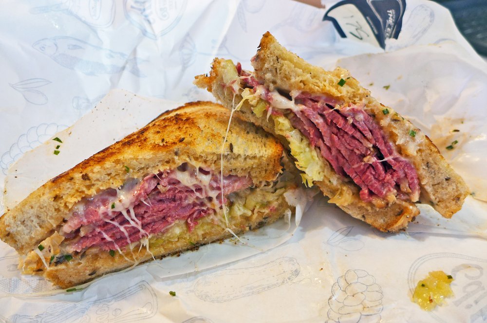 A meaty sandwich cut in half and served in paper.