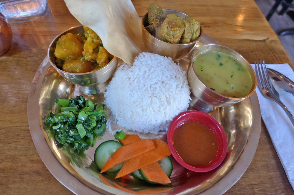 A silver tray covered with smaller trays of condiments and food.
