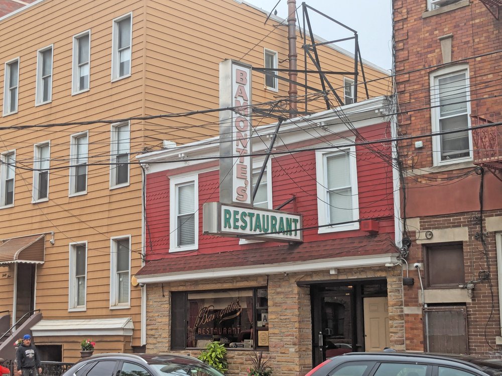 A restaurant in a red shingle building with brick columns.