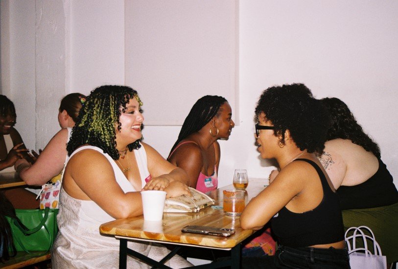 Women talk at tables.