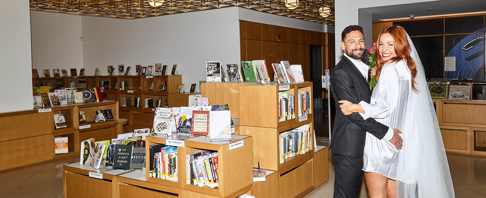 A couple poses in a bookshop.