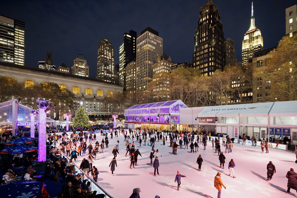 An outdoor ice skating rink at night, lit up by buildings.