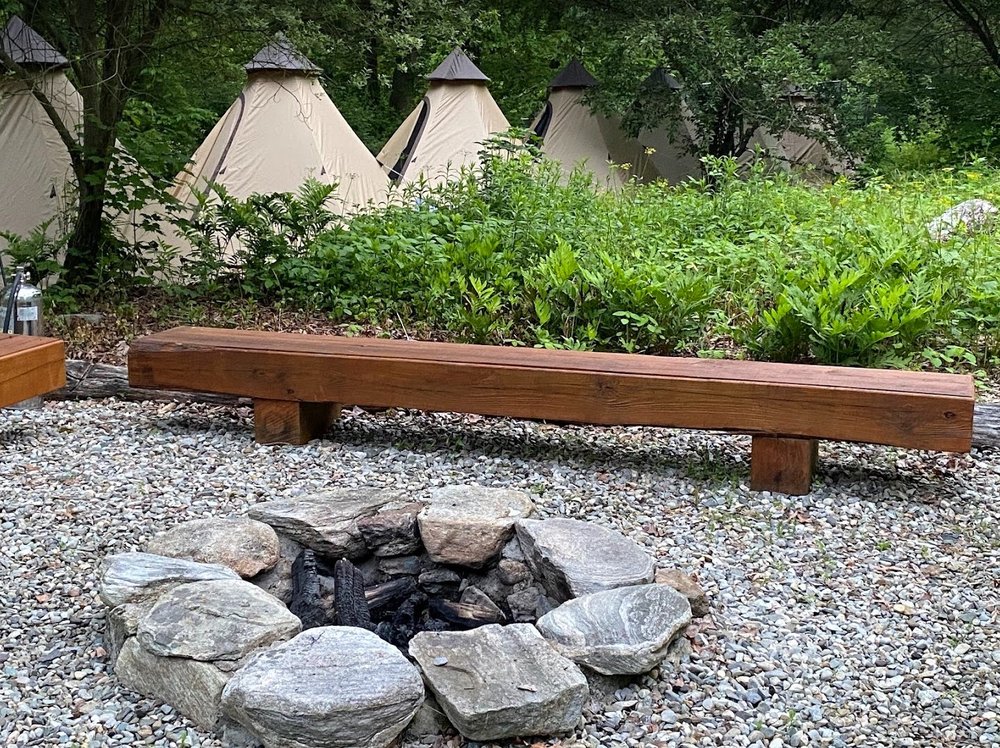 An outdoor firepit with tents in the background.