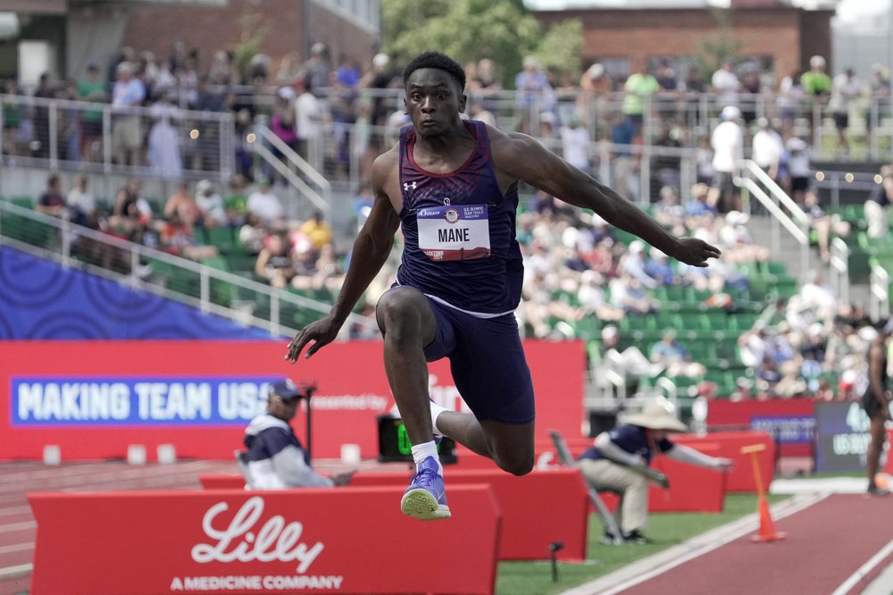 A track and field athlete jumps in the air at a competition.