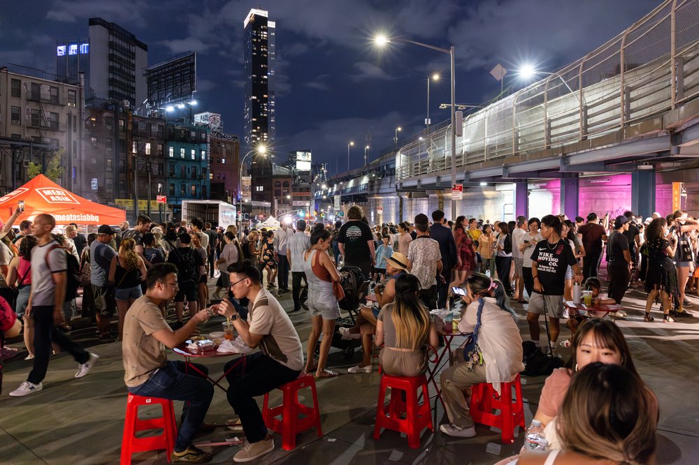 A group of people sitting at small tables outside.