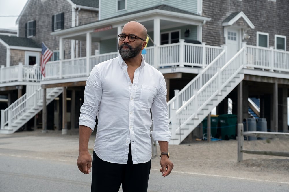 A man in a white shirt stands in front of a house