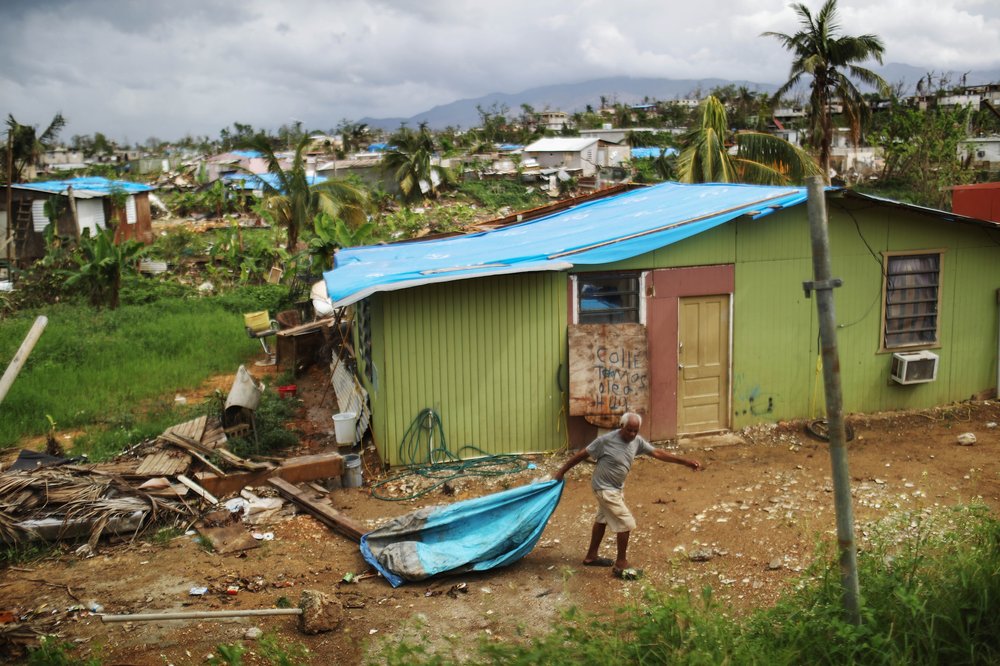 A local resident cleans debris near his damaged home in an area without electricity on October 15, 2017 in San Isidro, Puerto Rico. <br/>