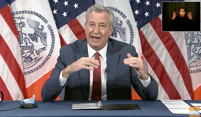 Mayor Bill de Blasio seats at a table and makes an announcement about reopening public schools on November 29th.