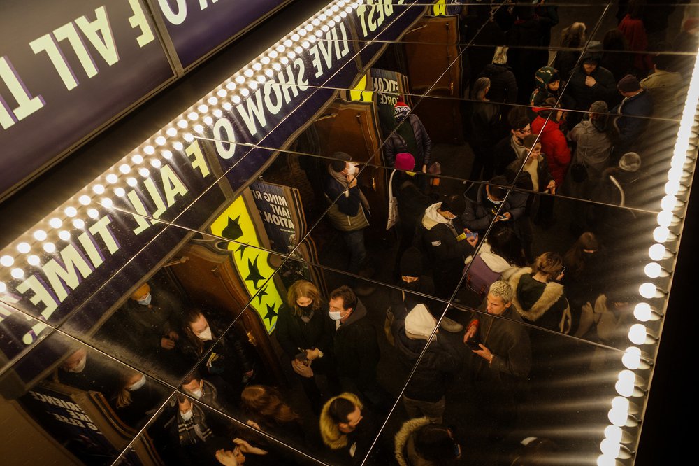 People standing under a ceiling mirror at a Broadway show.