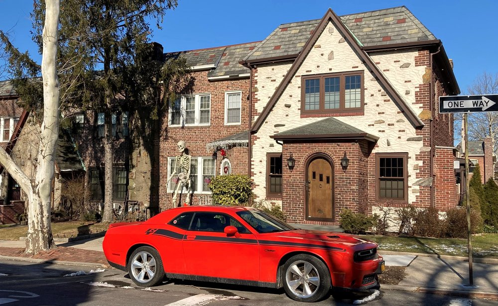 a red sports car parked in front of a Queens house