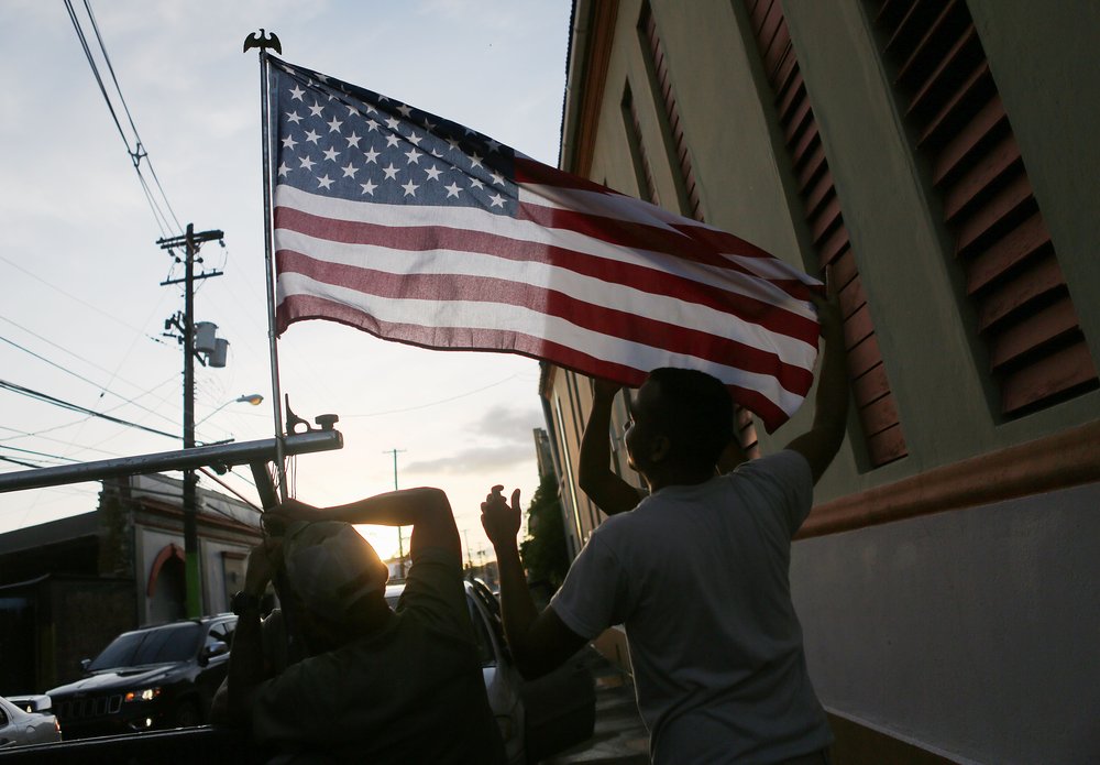 Army reserve soldiers, from Puerto Rico, attach an American flag to one of their vehicles, in an area with a sporadic electricity supply, on October 14, 2017 in Yauco, Puerto Rico. <br/>