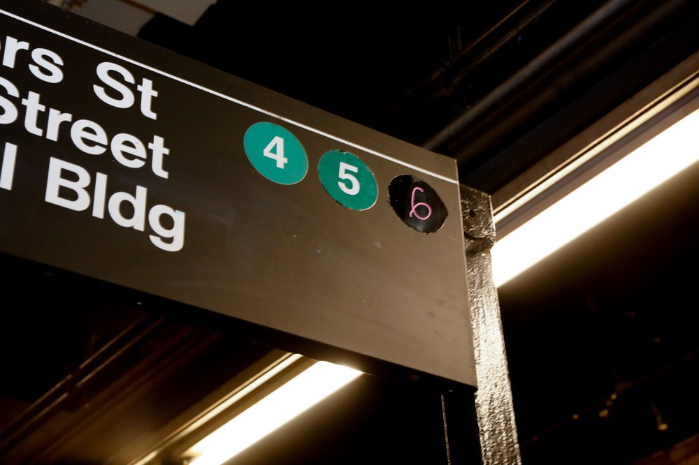 A photo of a wayfinding sign at Chambers street, where the notice for the 6 train is written in marker.