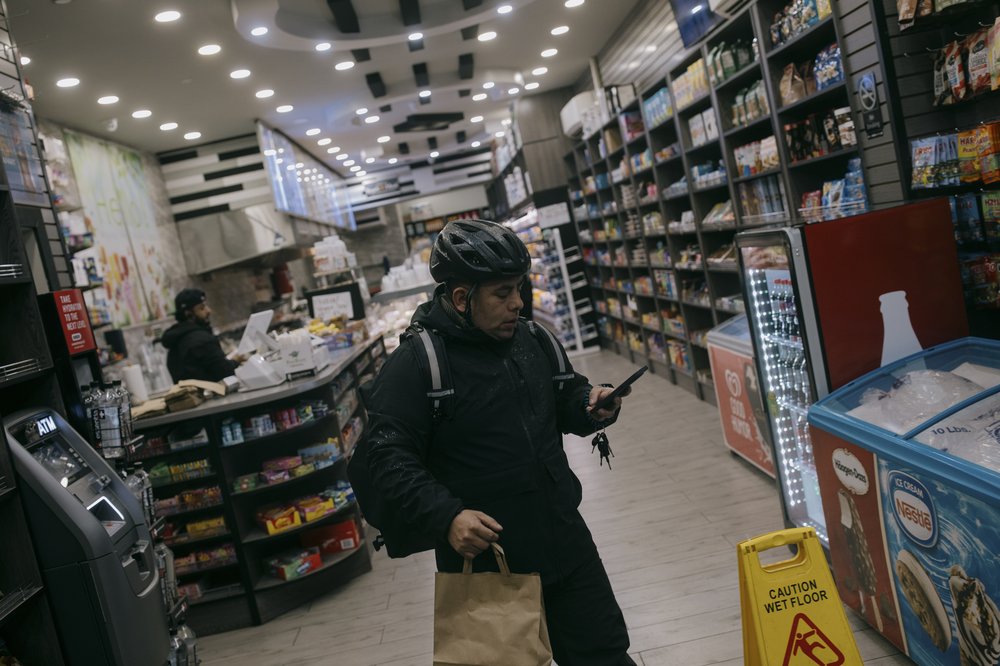 Gustavo Ajche, a delivery driver and member of Los Deliveristas Unido, picks up a customer's order from Pace Gourmet Deli in Manhattan.