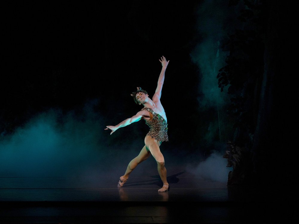 A man dances in a green costume on a stage