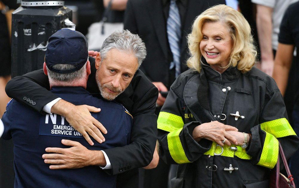 e1bf3300dshutterstock_10327123g-jpg.jpeg Jon Stewart embraces an NYPD officer alongside Congresswoman Carolyn Maloney. (Erik Pendzich/Shutterstock)