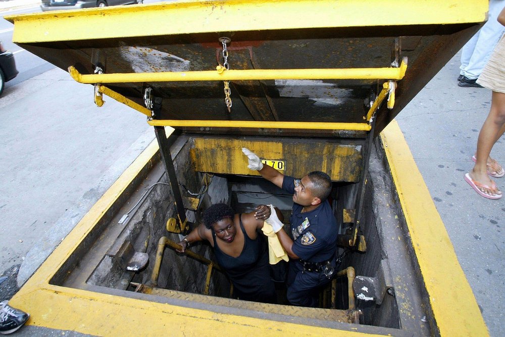 A police officer helps a subway passenger out of an exit on August 14, 2003 (Jason Szenes / EPA/Shutterstock)
