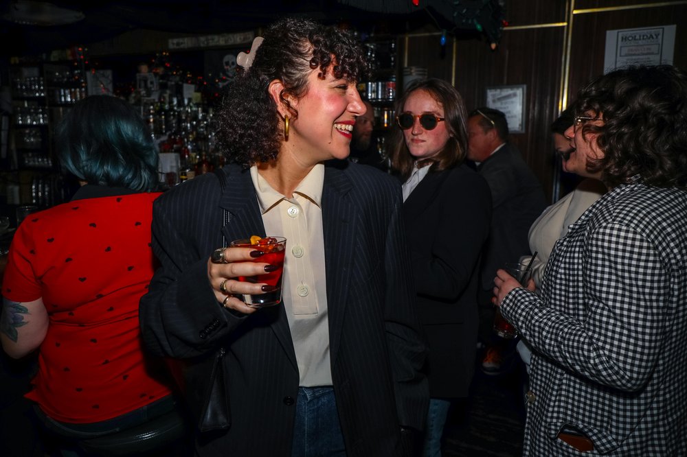 francon-19.jpg A person dressed as Fran Lebowitz holds a drink.