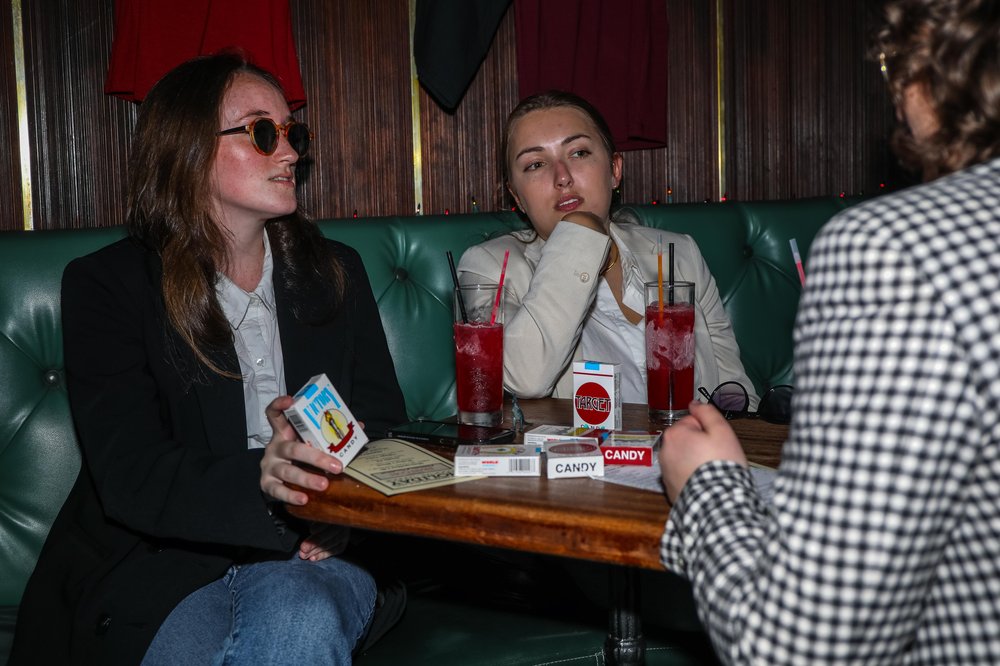 francon-5.jpg Two people sit at a booth dressed like Fran Lebowitz.