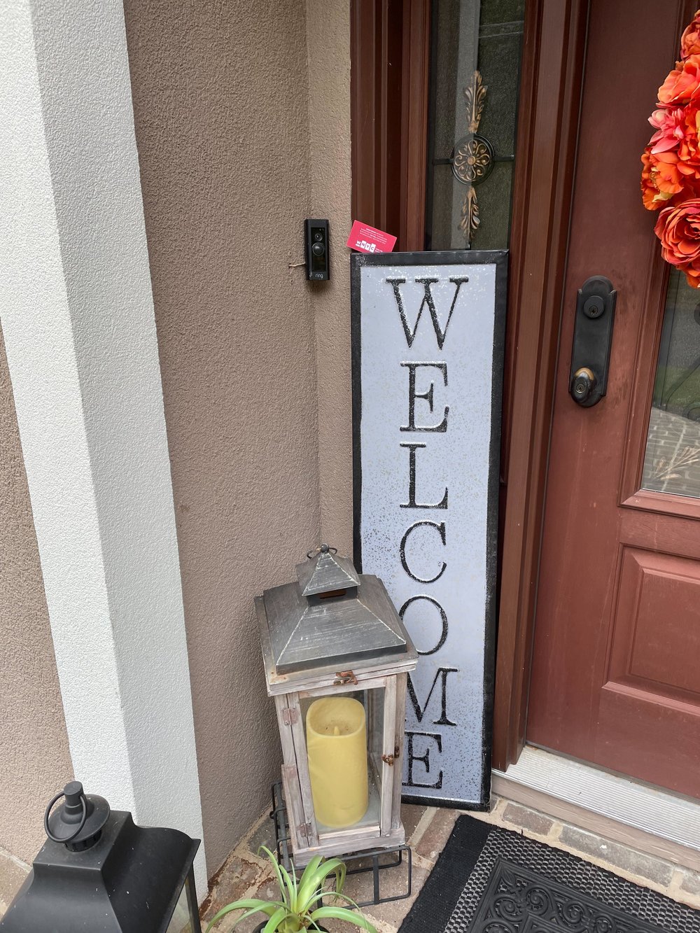 A welcome sign at a door with a red business card wedged in the top
