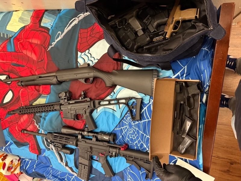 A photo released by prosecutors shows a cache of weapons recovered from a Bronx apartment, including multiple rifles and handguns.