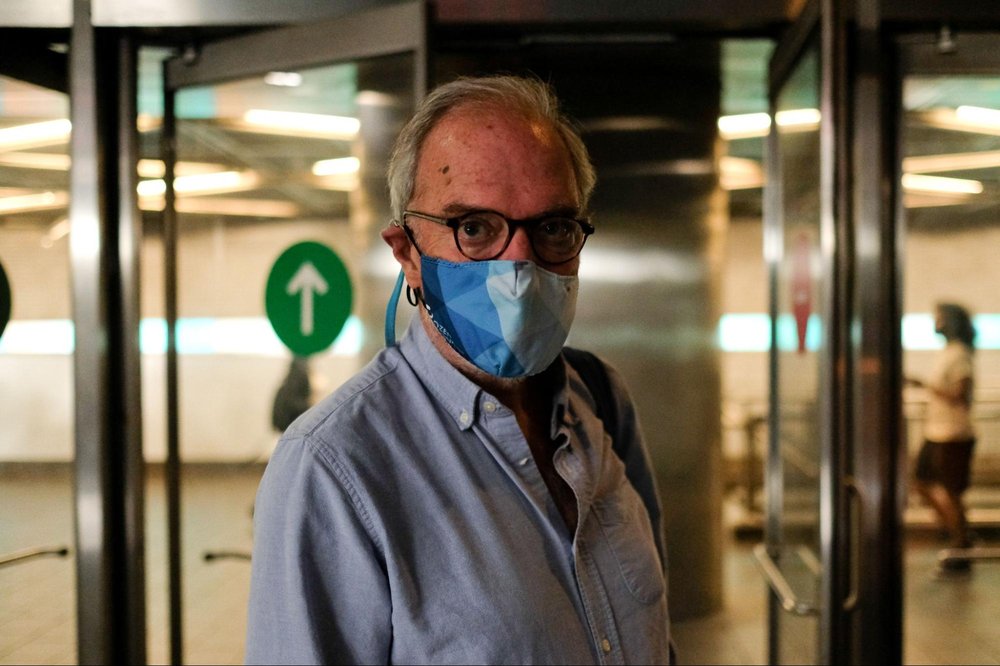 A man wears a mask while standing in a subway station