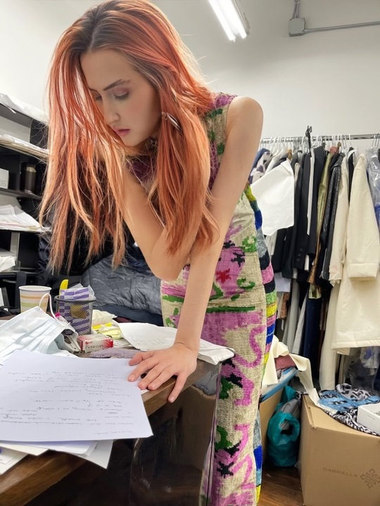 A woman in a dress looks over a paper