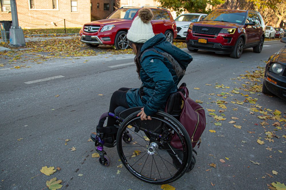 Katherine Valdez crosses the street in Briarwood in her wheelchair