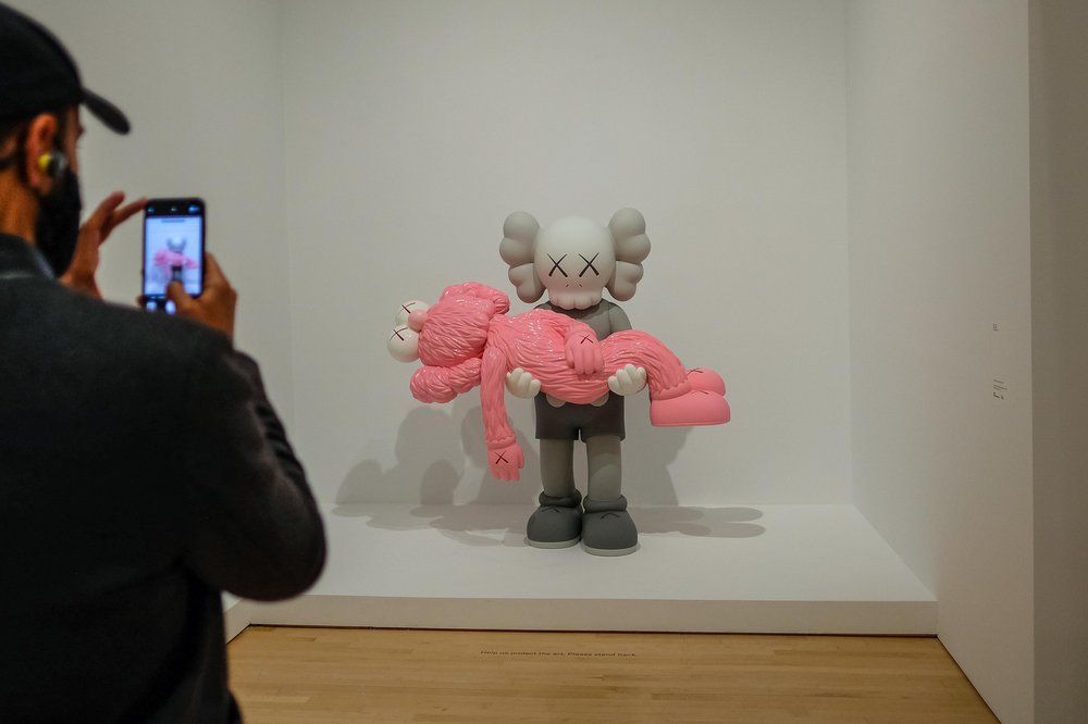 KAWS Brooklyn Museum One sculpture carrying another pink sculpture. Inside the KAWS exhibit at Brooklyn Museum
