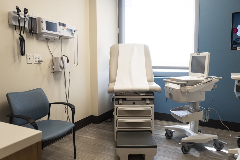 A medical exam room with a bed in the upright position, and an EKG machine.